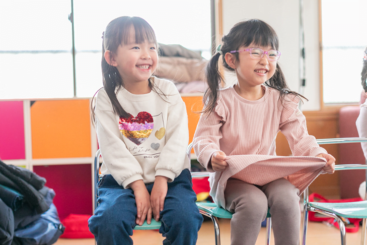 Two young girls laughing and smiling during a fun lesson at Rocket English School・ロケットイングリッシュスクールでの楽しいレッスン中、2人の少女が笑みを浮かべている