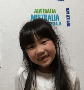 A young girl smiling shyly at the camera・カメラに向かって恥ずかしそうに微笑む少女