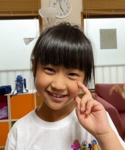 A young girl smiling and making a peace sign with her fingers・笑顔で指でピースサインをする少女