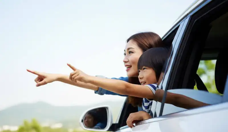 車の窓から母親と息子が指をさしている様子。